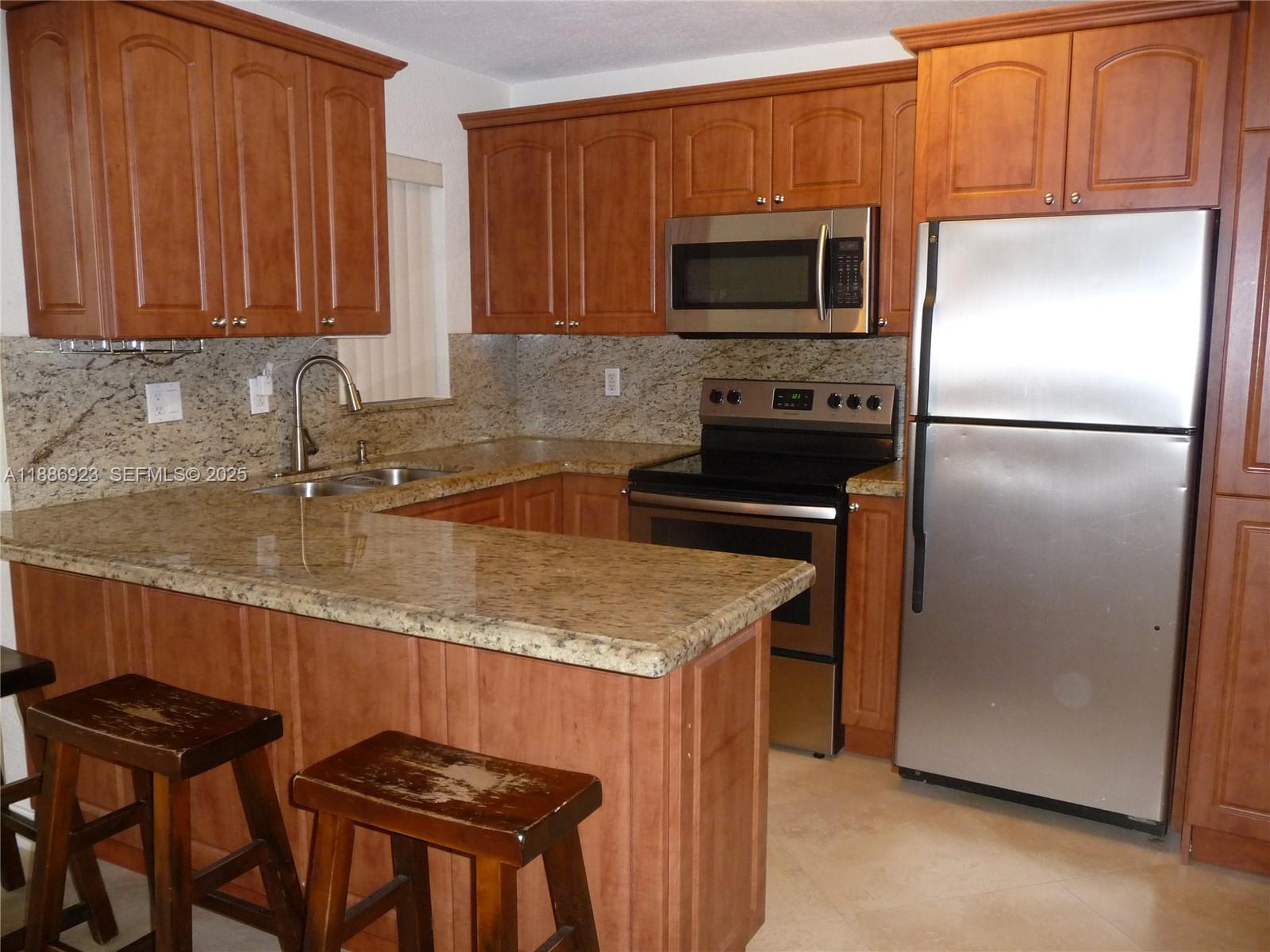 13904 Southwest 65th Terrace, Unit 8 Miami, FL 33183 - Photo 10 of 24 a kitchen with granite countertop a refrigerator stove and microwave