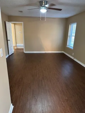 an empty room with wooden floor fan and windows
