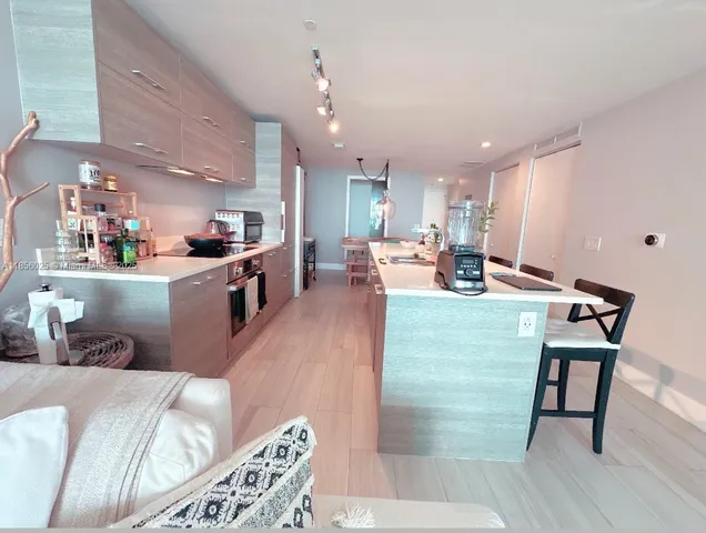 a living room with stainless steel appliances furniture and a kitchen view