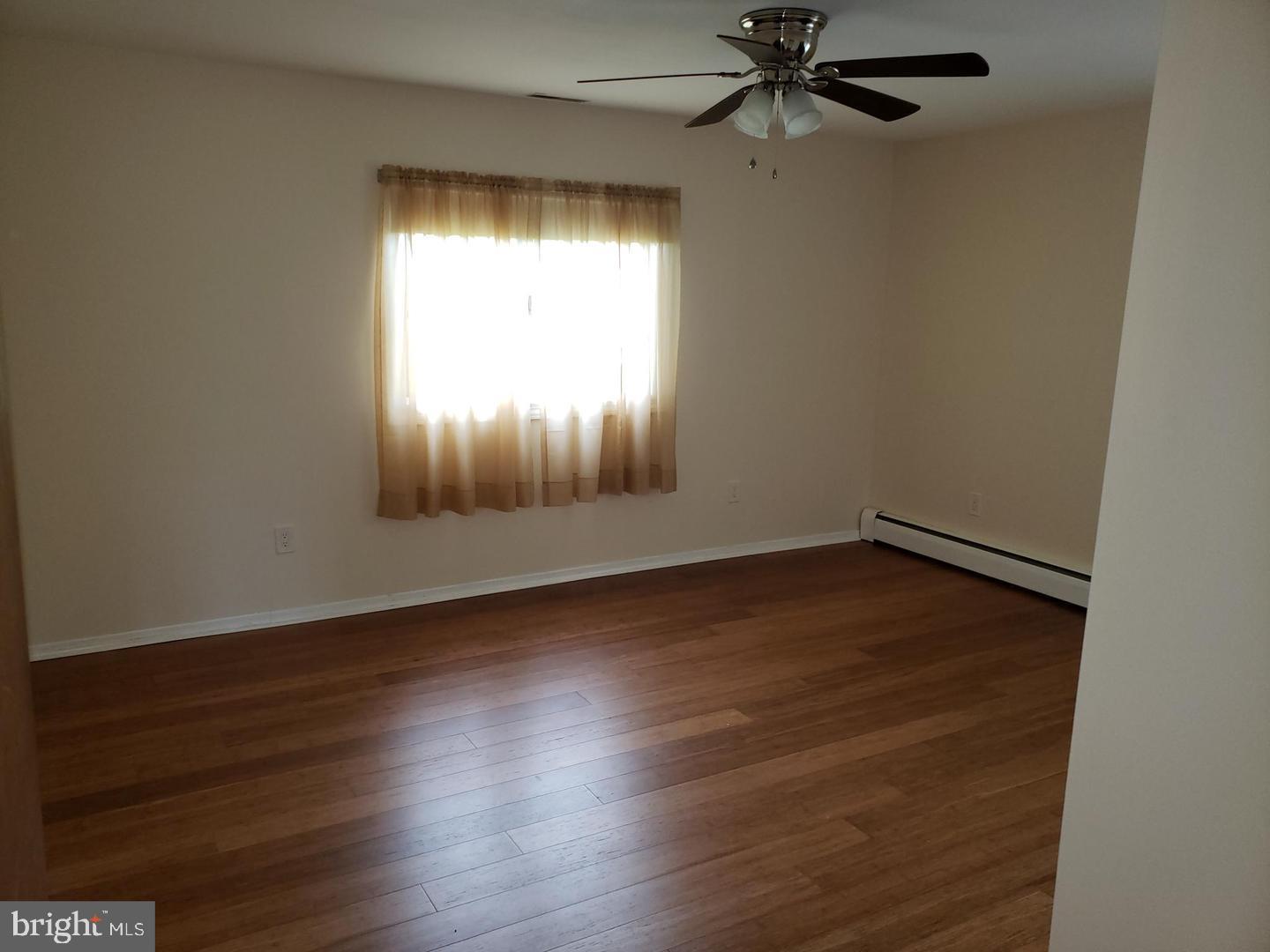 102 Gilbert Road Bordentown, NJ 08505 - Photo 11 of 28 an empty room with wooden floor chandelier fan and windows