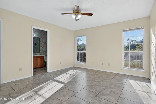 a view of a livingroom with a chandelier fan and windows