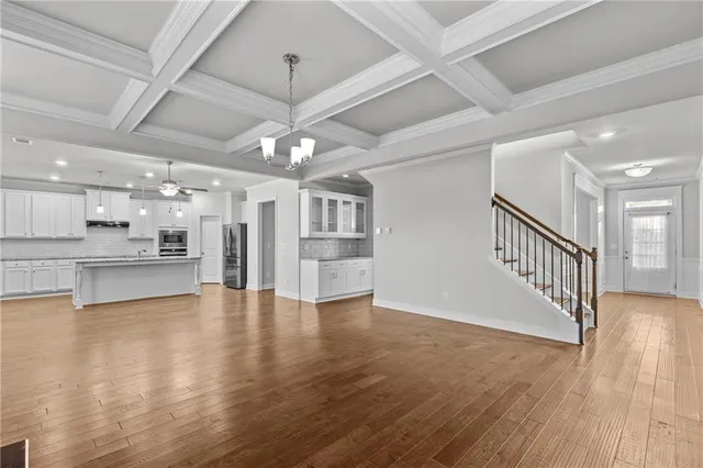 a view of a hallway with wooden floor and a kitchen