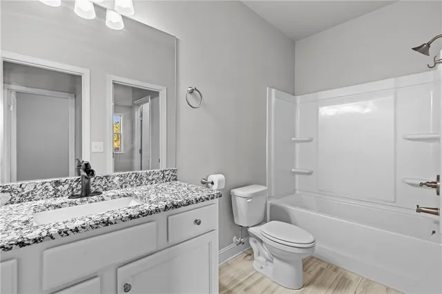 a bathroom with a granite countertop toilet a sink and a bathtub