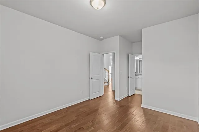 a view of an empty room with wooden floor and window