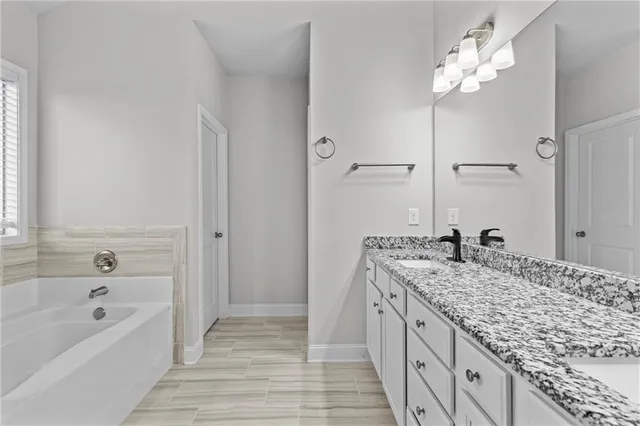 a bathroom with a granite countertop sink a bathtub and shower