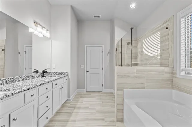 a bathroom with a tub sink and mirror