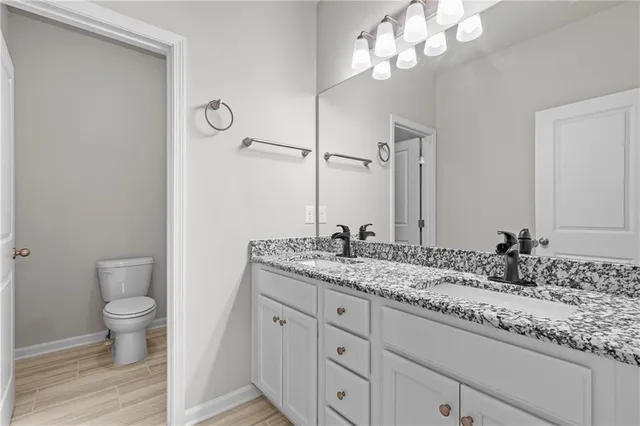 a bathroom with a granite countertop sink a toilet and a mirror