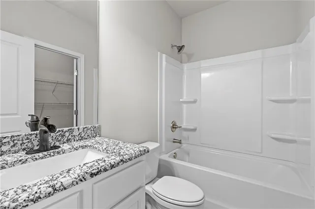a bathroom with a granite countertop sink toilet mirror and bathtub