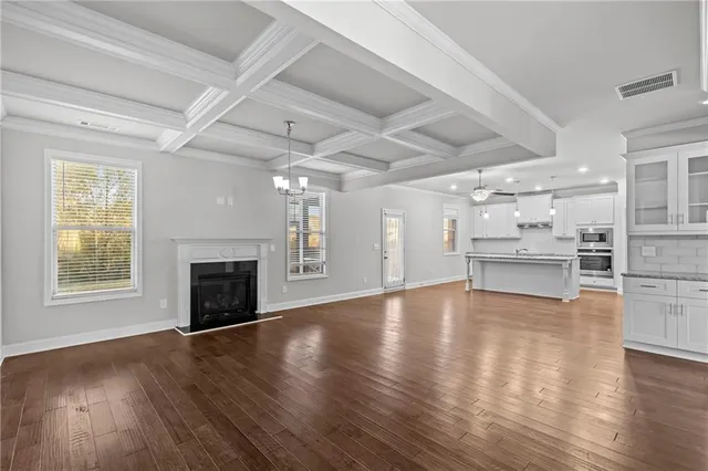 a view of an empty room with wooden floor a fireplace and windows