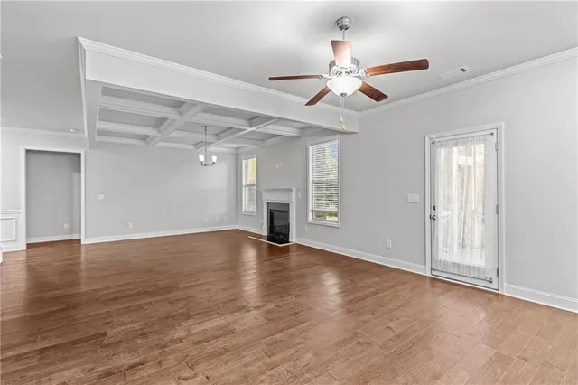 an empty room with wooden floor chandelier fan and windows