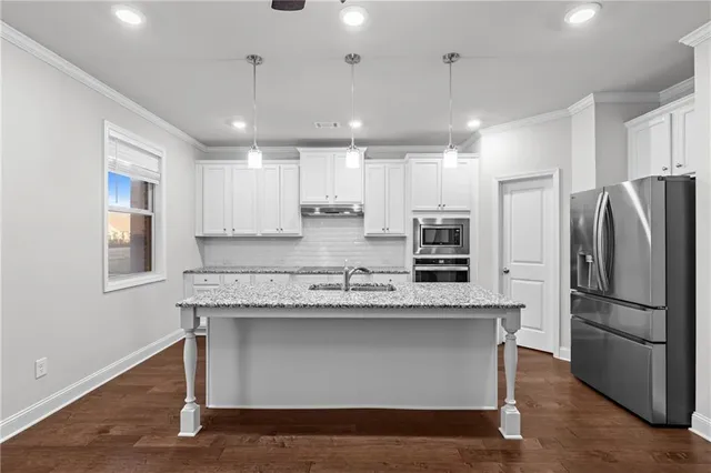 a kitchen with kitchen island stainless steel appliances a sink and a refrigerator