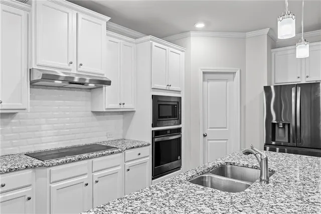 a kitchen with granite countertop a sink stove and refrigerator