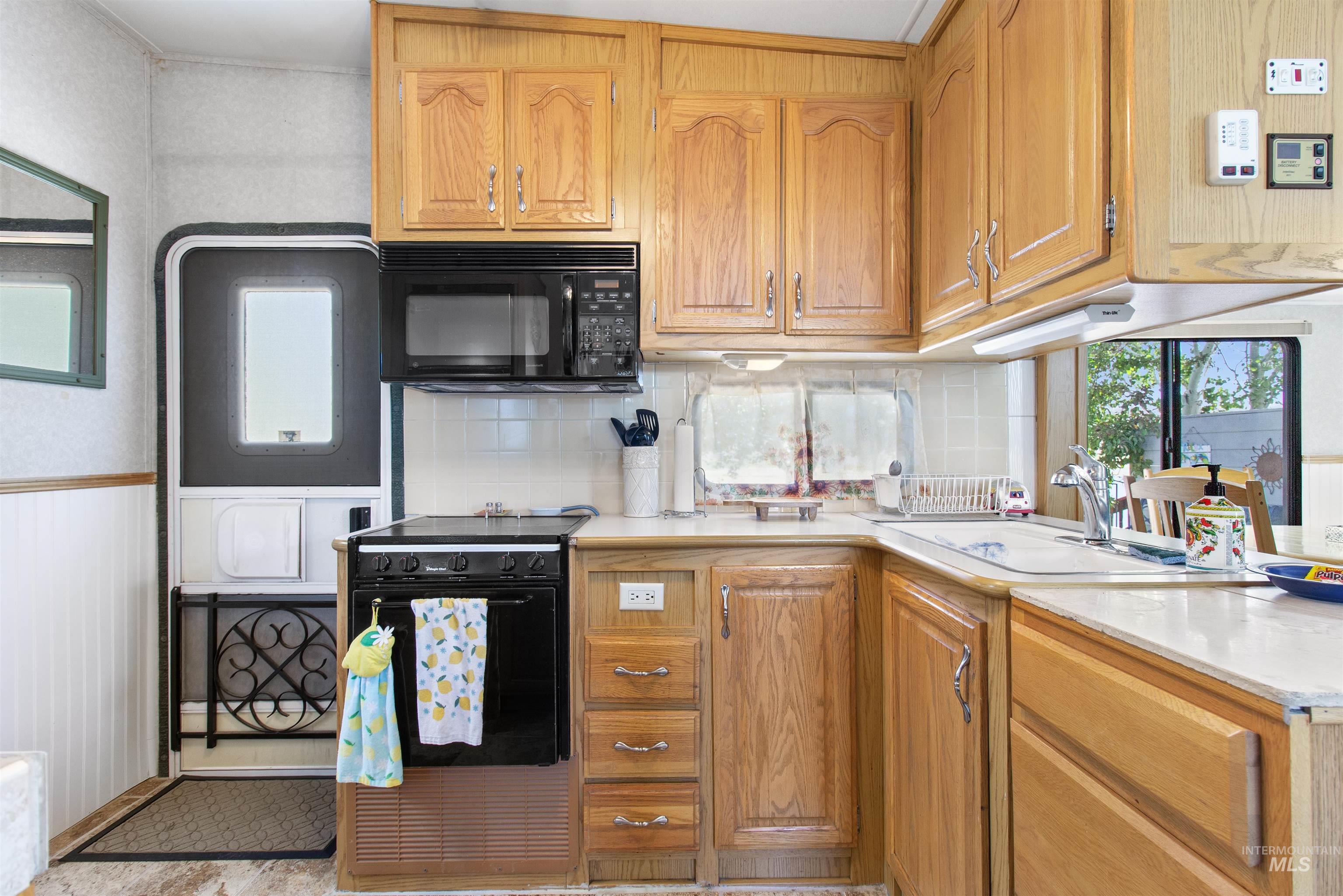 106 West Magic Road Shoshone, ID 83352 - Photo 18 of 45 Kitchen featuring wood-finish cabinetry, integrated microwave, built-in oven with stovetop, stainless steel sink, and light-toned countertops