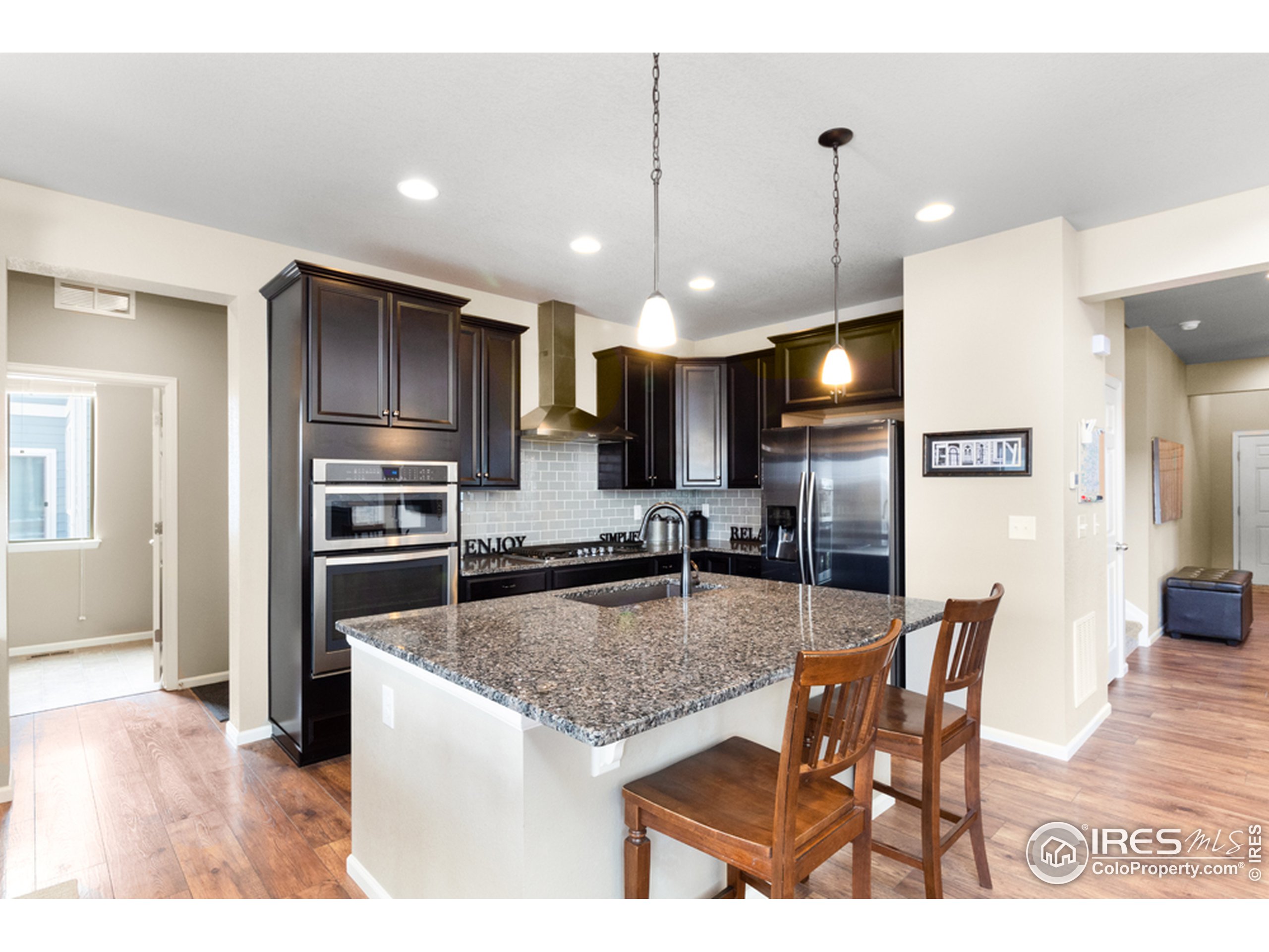 6559 Tombstone Ridge Road Timnath, CO 80547 - Photo 9 of 30 a kitchen with granite countertop kitchen island stainless steel appliances a refrigerator a stove a sink a dining table and chairs