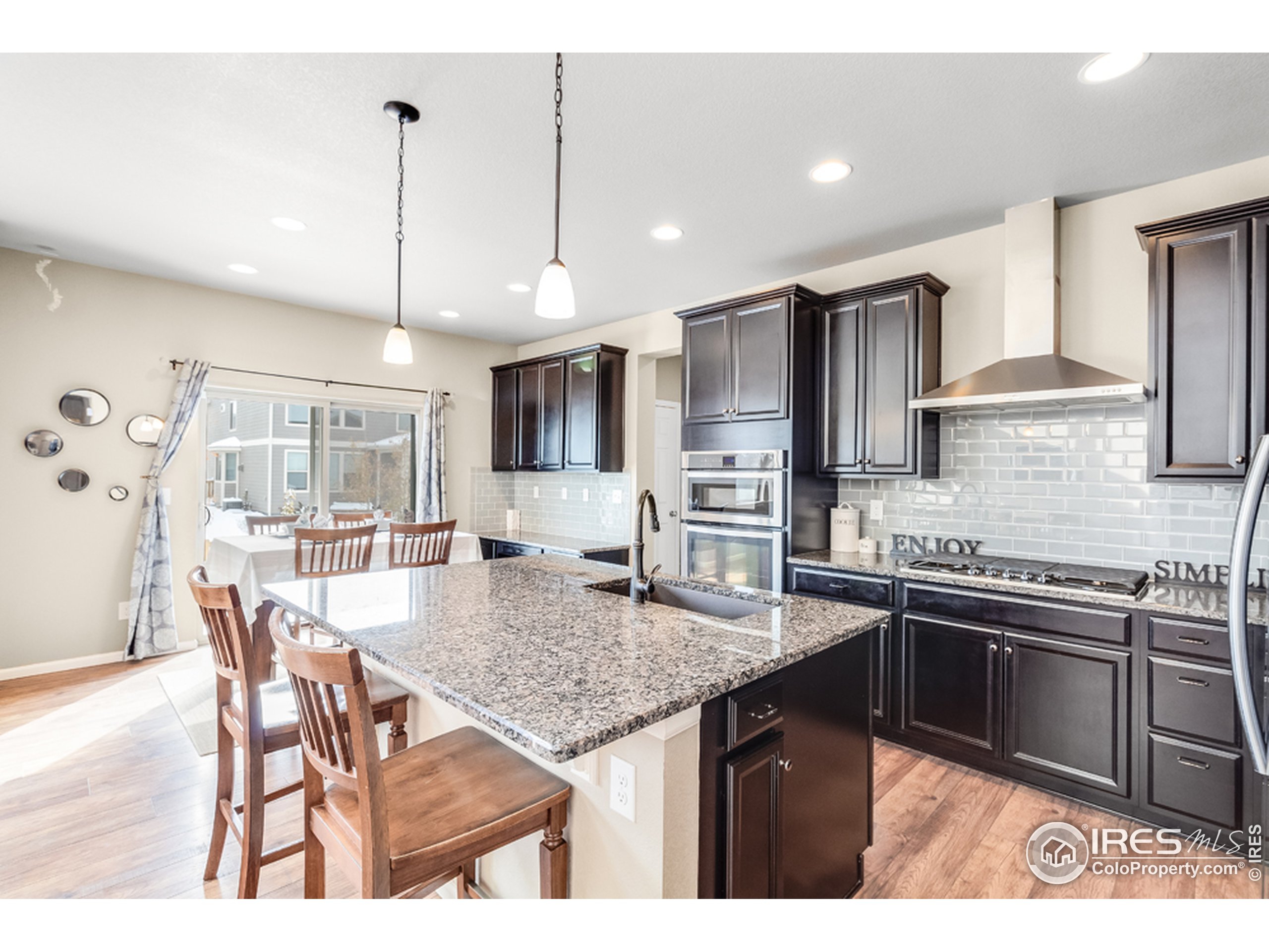 6559 Tombstone Ridge Road Timnath, CO 80547 - Photo 10 of 30 a kitchen with stainless steel appliances granite countertop a kitchen island a stove a table and chairs