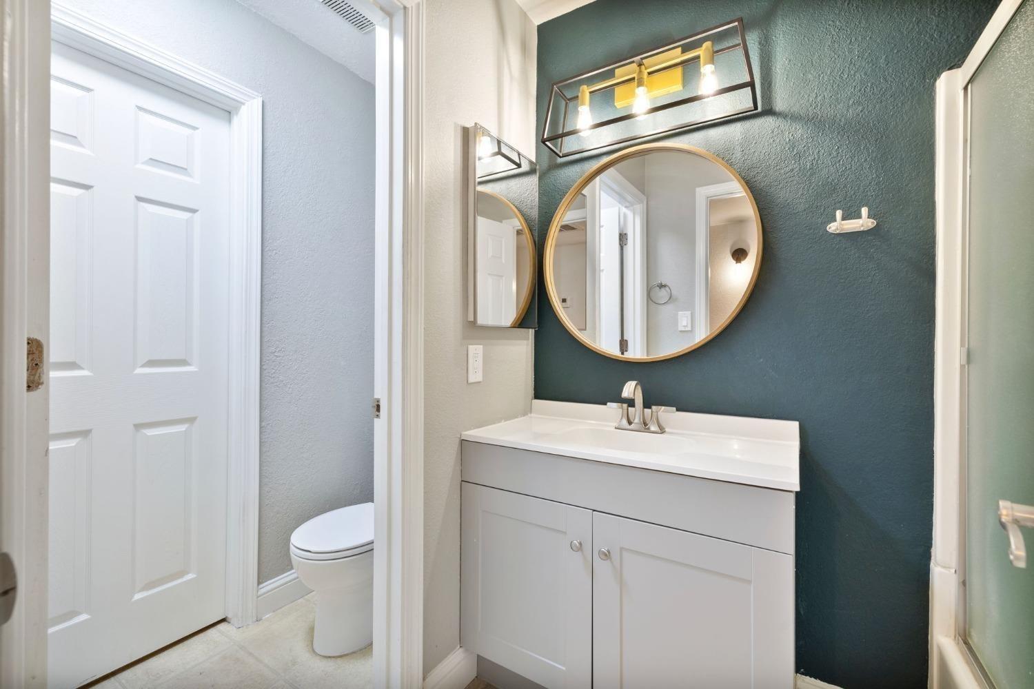 2881 Huntington Boulevard, Unit 212 Fresno, CA 93721 - Photo 12 of 17 a bathroom with a toilet sink vanity and mirror