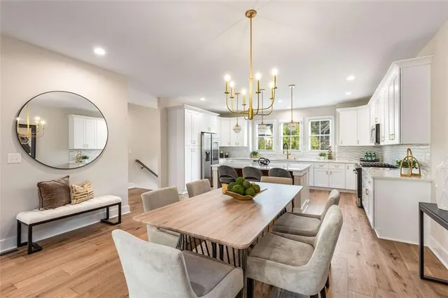 a living room with couches a dining table with kitchen view and wooden floor
