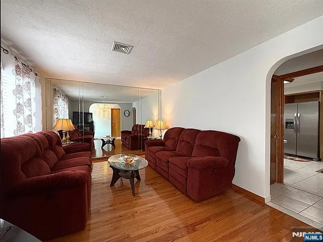 a kitchen with granite countertop a refrigerator a stove a sink dishwasher a dining table and chairs with wooden floor