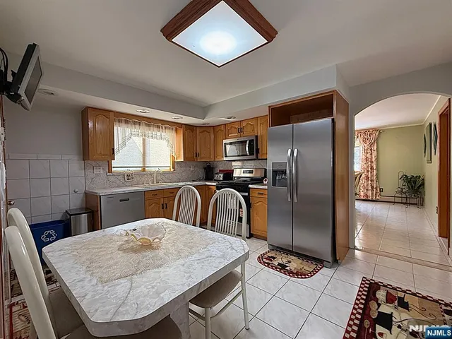 a kitchen with stainless steel appliances granite countertop a refrigerator a sink a stove top oven and a dishwasher next to a window