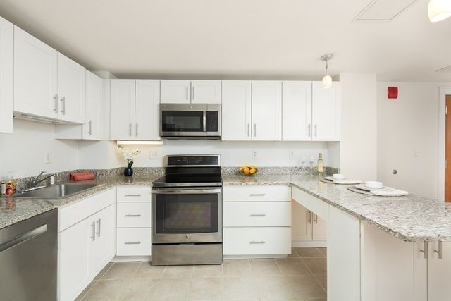 a kitchen with granite countertop white cabinets sink and white appliances
