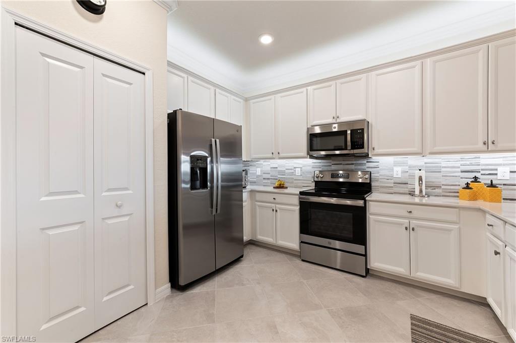 2652 Vine Avenue Naples, FL 34120 - Photo 11 of 40 a kitchen with stainless steel appliances white cabinets and a refrigerator