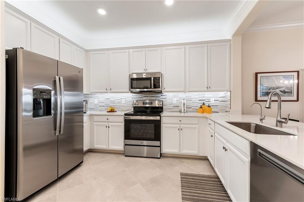 2652 Vine Avenue Naples, FL 34120 - Photo 9 of 40 a kitchen with white cabinets and stainless steel appliances