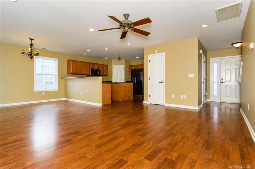 87 Yadkin Road, Unit 327 Fletcher, NC 28732 - Photo 4 of 23 a view of an empty room and kitchen with wooden floor and a ceiling fan
