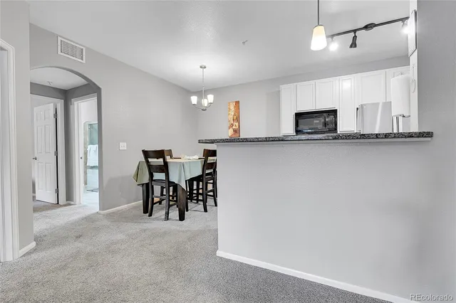 a kitchen with stainless steel appliances granite countertop a sink a stove a microwave a dining table and chairs with wooden floor