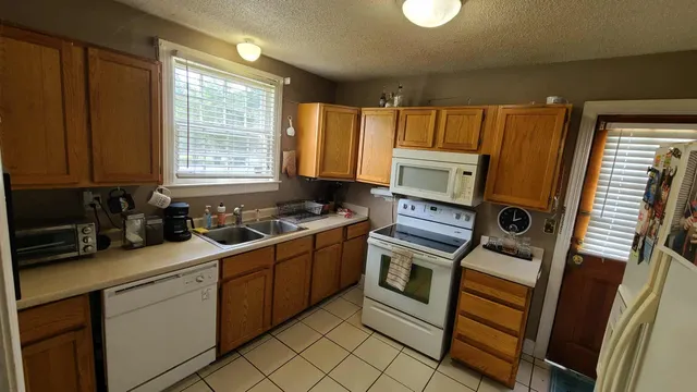 a kitchen with granite countertop a refrigerator stove and sink