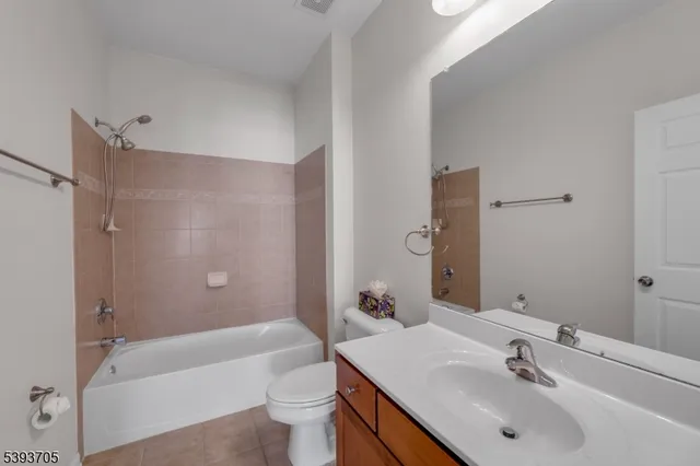 a bathroom with a bathtub shower sink vanity mirror and toilet