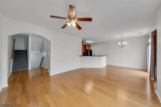 a view of an empty room with wooden floor and a ceiling fan