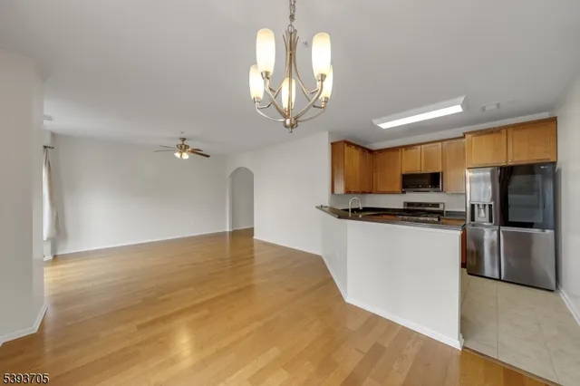 a kitchen with stainless steel appliances granite countertop a refrigerator a sink dishwasher a stove and a dining table with wooden floor