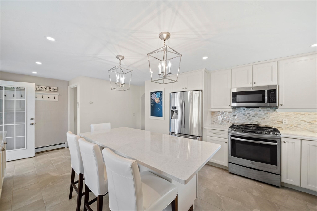 103 Williston Road Bourne, MA 02562 - Photo 5 of 40 a kitchen with stainless steel appliances a stove a table and chairs in it