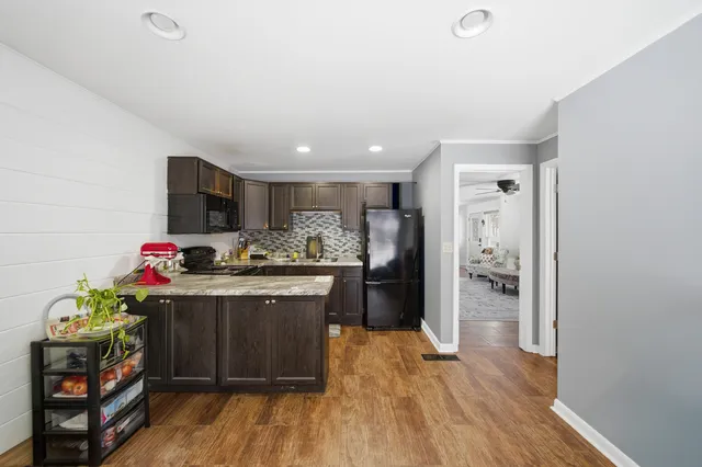 a kitchen with stainless steel appliances kitchen island granite countertop a refrigerator and a wooden cabinets
