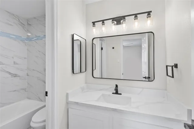 a bathroom with a granite countertop sink a toilet and a mirror