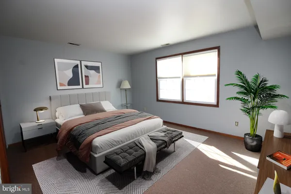a bedroom with a bed a couch and a potted plant