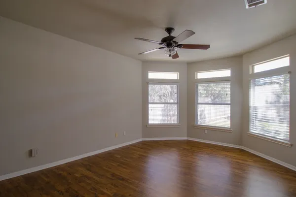a view of an empty room with a window and wooden floor