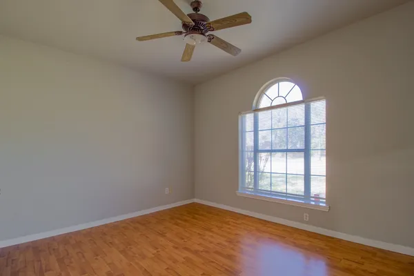 an empty room with windows and ceiling fan