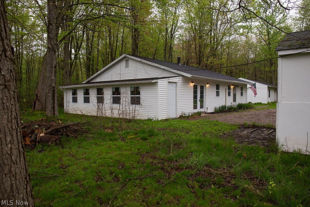 3644 Padanarum Road Geneva, OH 44041 - Photo 17 of 19 Single-story dwelling with white vinyl siding, a black shingle roof, and multiple exterior doors including a set of French doors