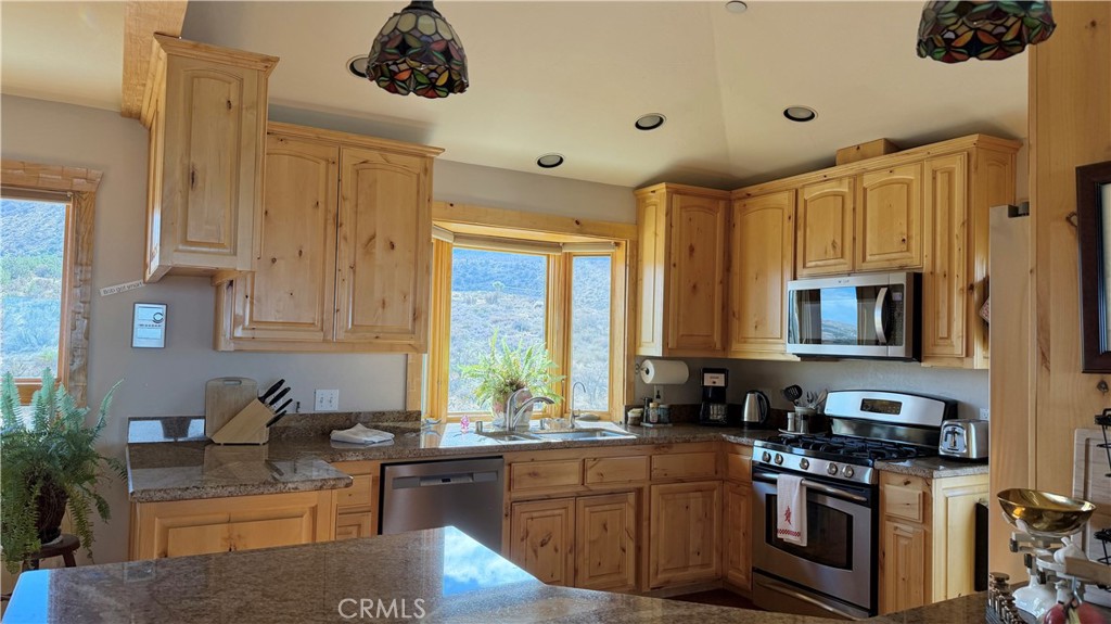 275 Canyon Road Pinon Hills, CA 92372 - Photo 19 of 68 a kitchen with stainless steel appliances granite countertop a stove a sink and a microwave