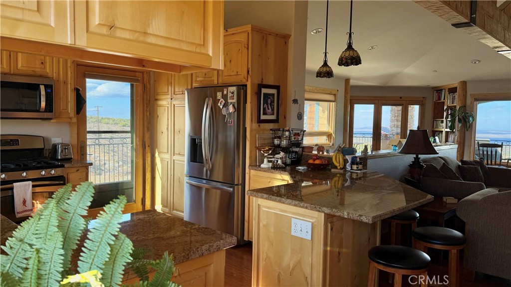 275 Canyon Road Pinon Hills, CA 92372 - Photo 20 of 68 a kitchen with stainless steel appliances granite countertop a refrigerator a stove and a sink with wooden floor