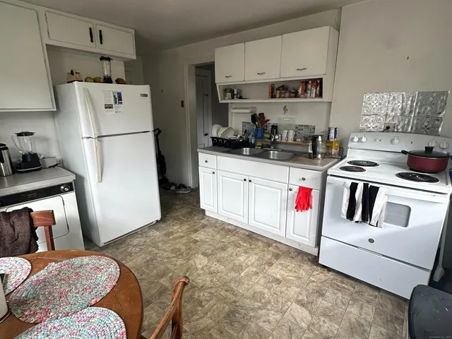 a kitchen with stainless steel appliances granite countertop a refrigerator sink stove and white cabinets