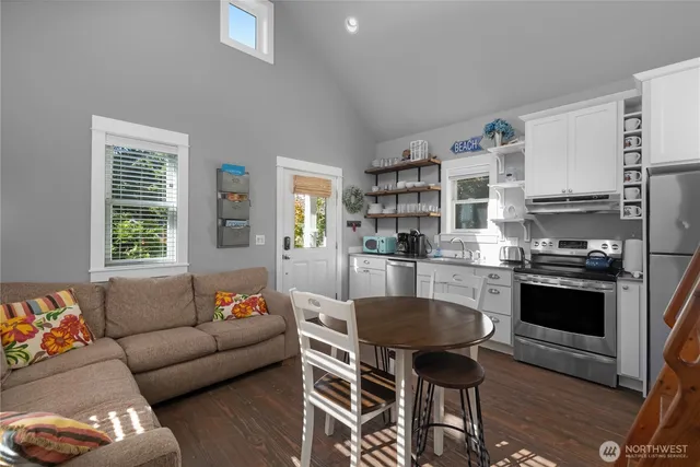 a living room with stainless steel appliances a dining table and a couch
