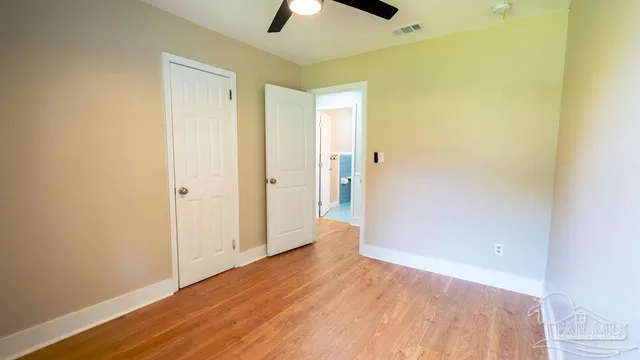 a view of an empty room with wooden floor and windows