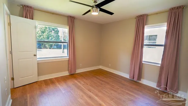 an empty room with wooden floor cabinet and windows