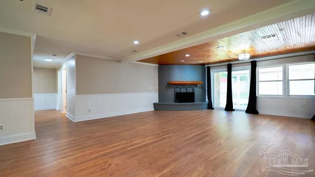an empty room with wooden floor fan and windows