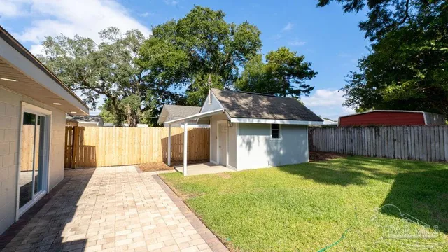 a backyard of a house with large trees and wooden fence