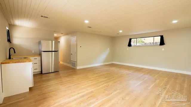 a view of a kitchen with refrigerator and wooden floor