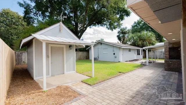 a view of a house with a yard and large tree