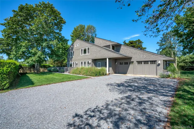 a view of a house with a yard and large trees